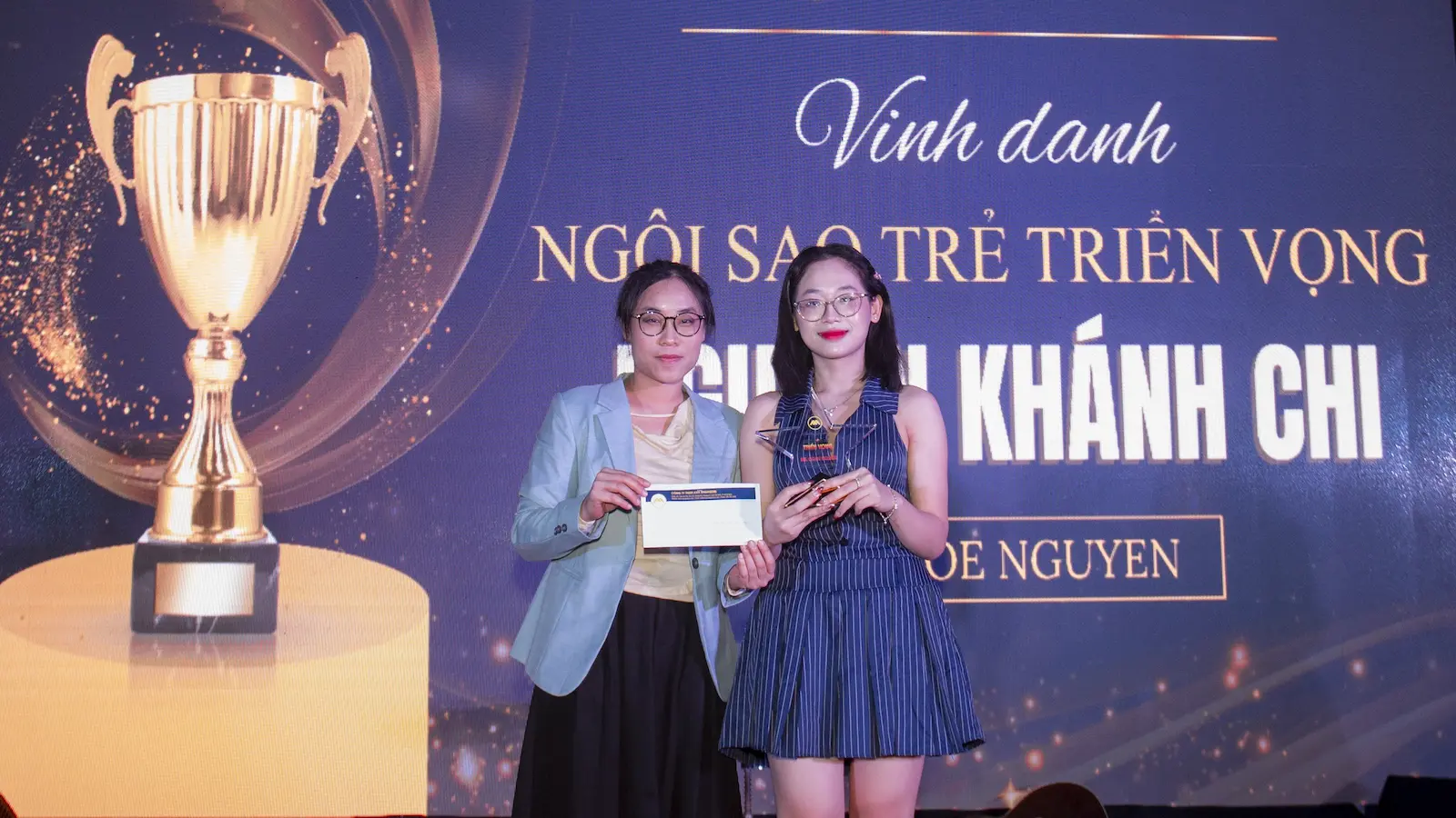 Tuyen Dung AXANH: Two women on stage with an award and certificate; AXANH tuyển dụng branding screen behind.