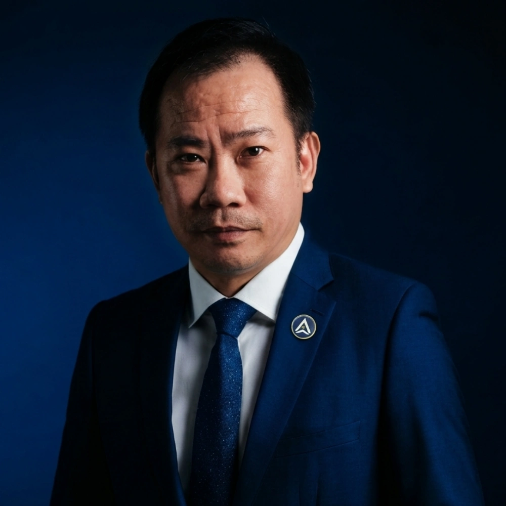 AXANH leader in blue suit and tie, facing camera, dark blue background.