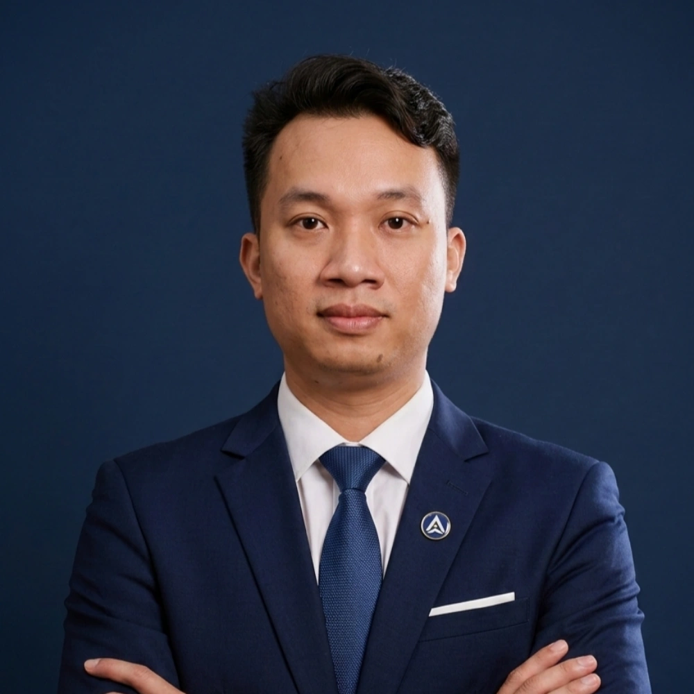 An AXANH leader in a navy suit stands with arms crossed, facing forward.