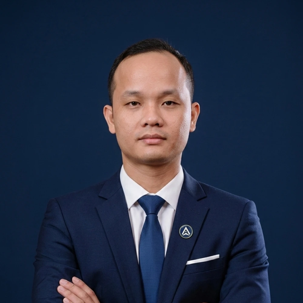 AXANH leader in dark blue suit stands with arms crossed, neutral expression.