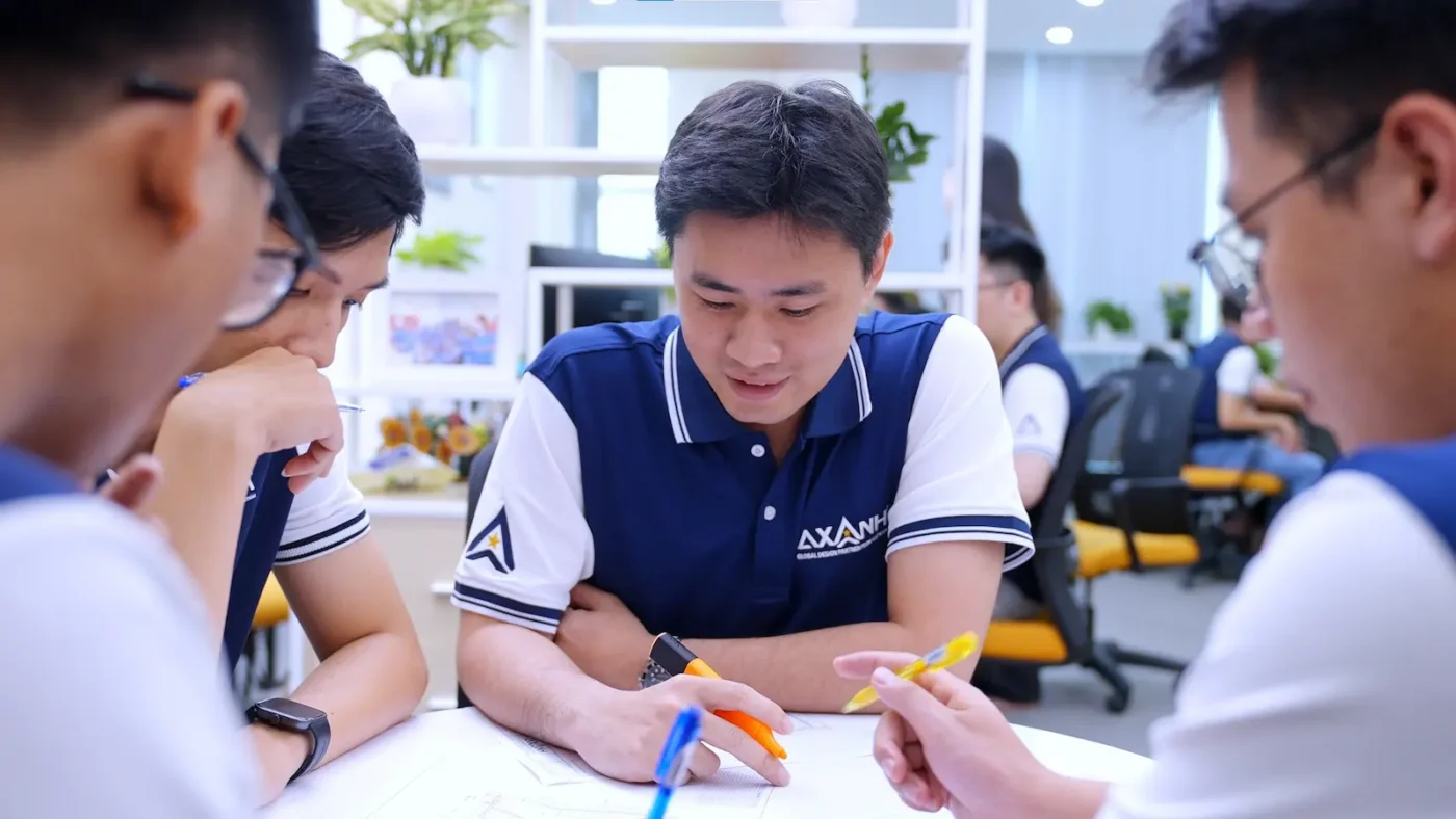 Four people in blue and white shirts discuss documents at a table.