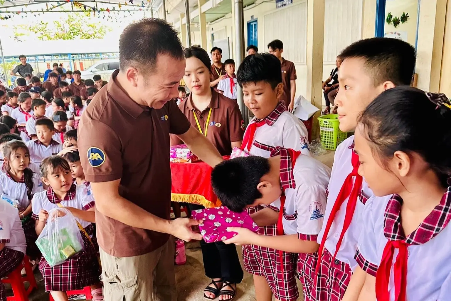 A man gives a wrapped gift to a bowing schoolboy in class.